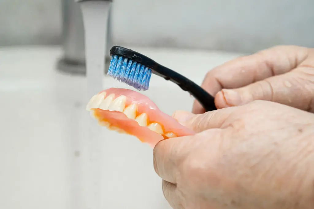 elderly woman brushing her full denture.