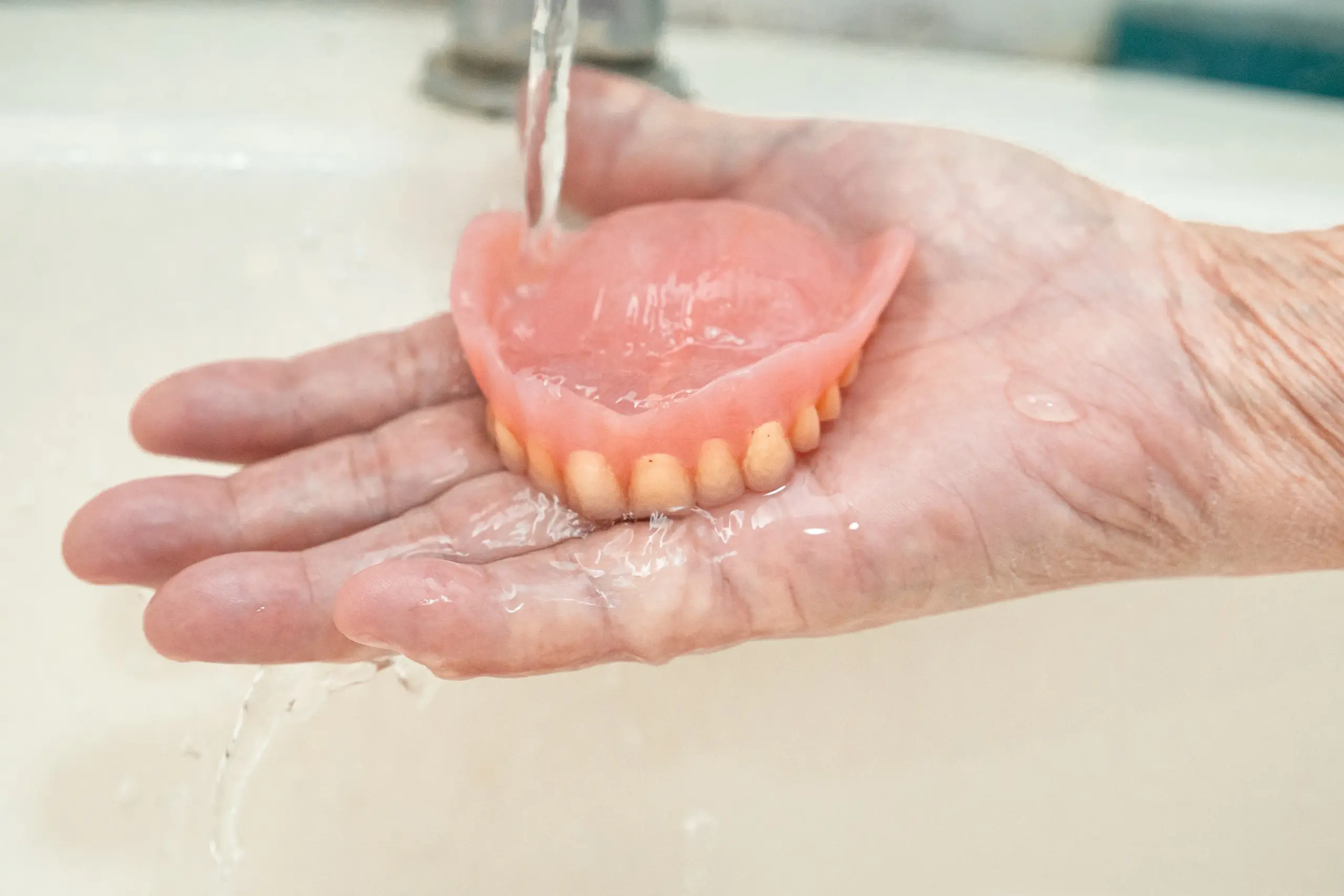 close up hand holding a denture.