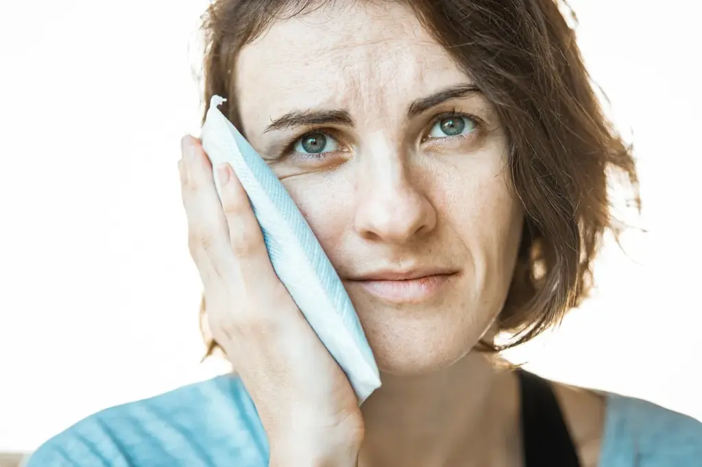 Cold compress on the cheek to reduce swelling and heal faster after dental implants.