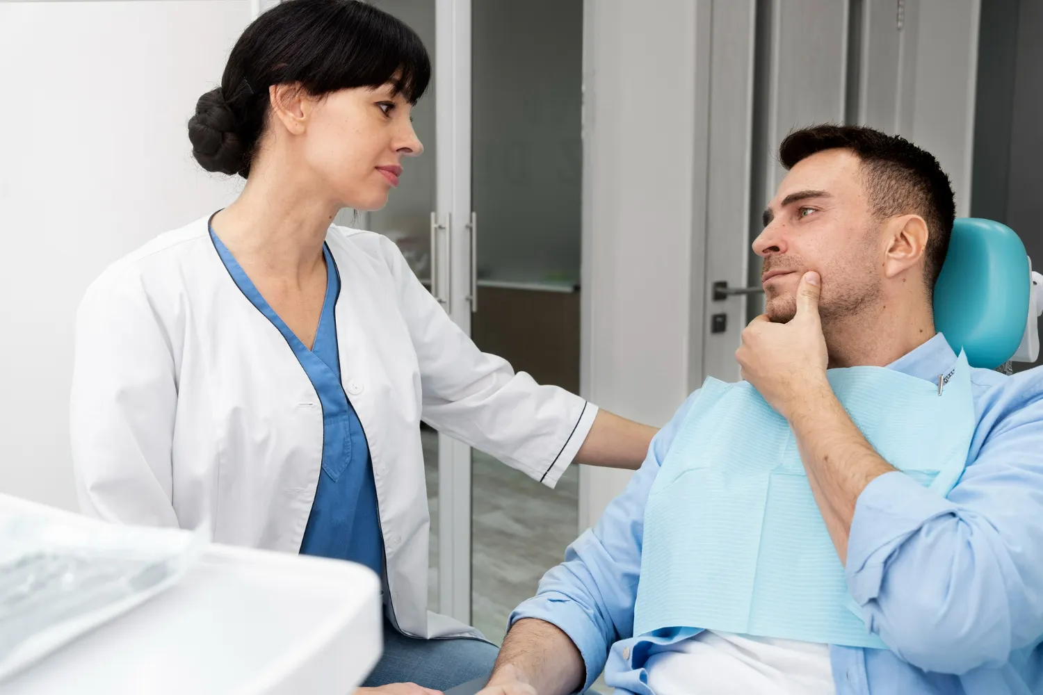 Dentist assessing a patient with dental pain during an emergency consultation in a calm clinical setting.