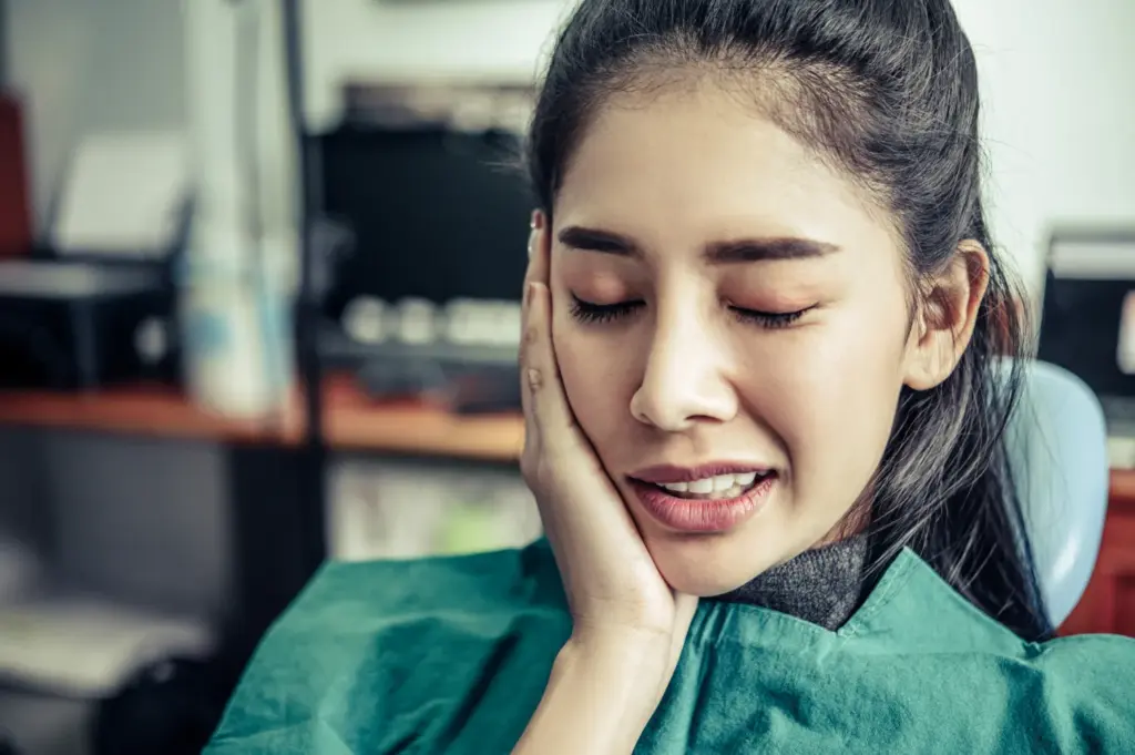 Patient experiencing toothache and facial discomfort, a common sign of emergency dental pain.
