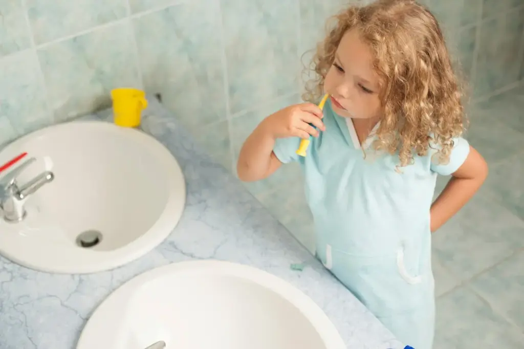 Child brushing teeth at the sink as part of a daily routine.