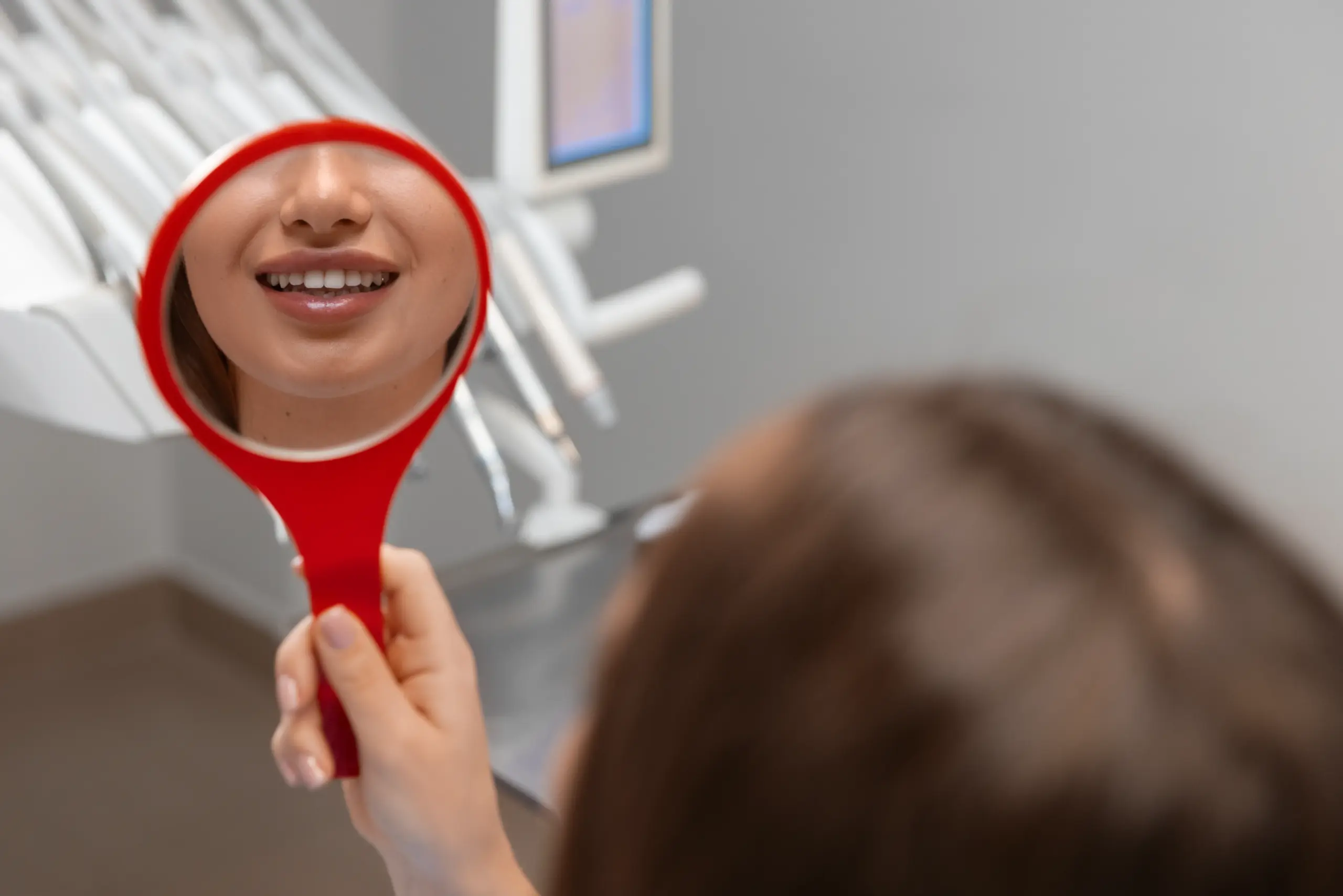 Patient checking brighter teeth in a dental mirror.