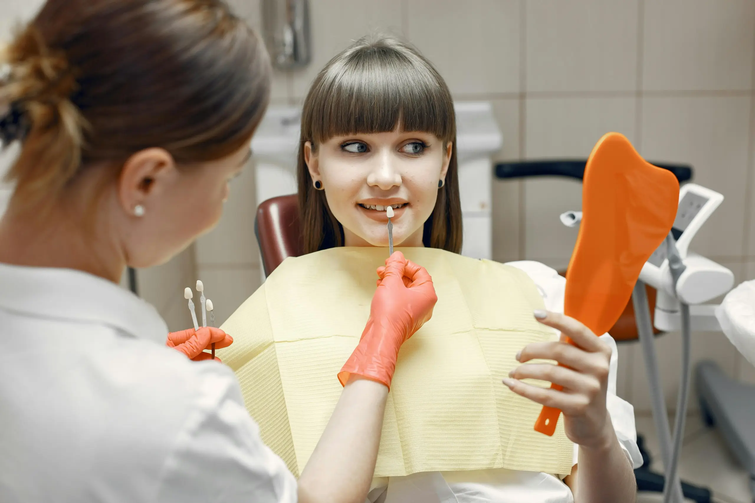 Patient comparing tooth shade during porcelain veneers planning.
