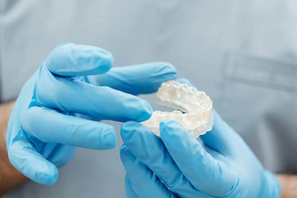 Dentist checking a clear aligner during an orthodontic review.