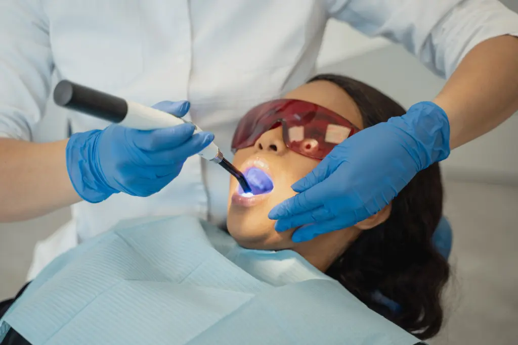 Dentist using a curing light during dental treatment.