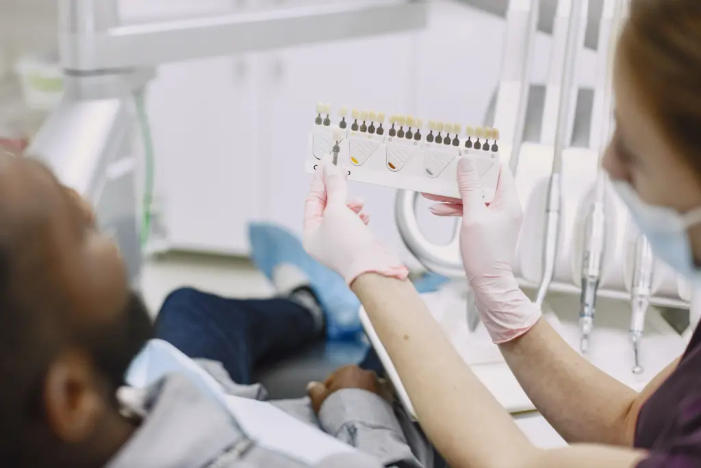 Dentist comparing tooth shades during treatment planning.
